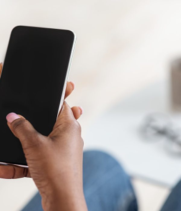 Unrecognizable Black Woman Using Smartphone With Blank Black Screen At Home, Checking New App Or Website, Browsing Internet, Spending Time With Gadget, Mockup Image With Empty Space, Closeup